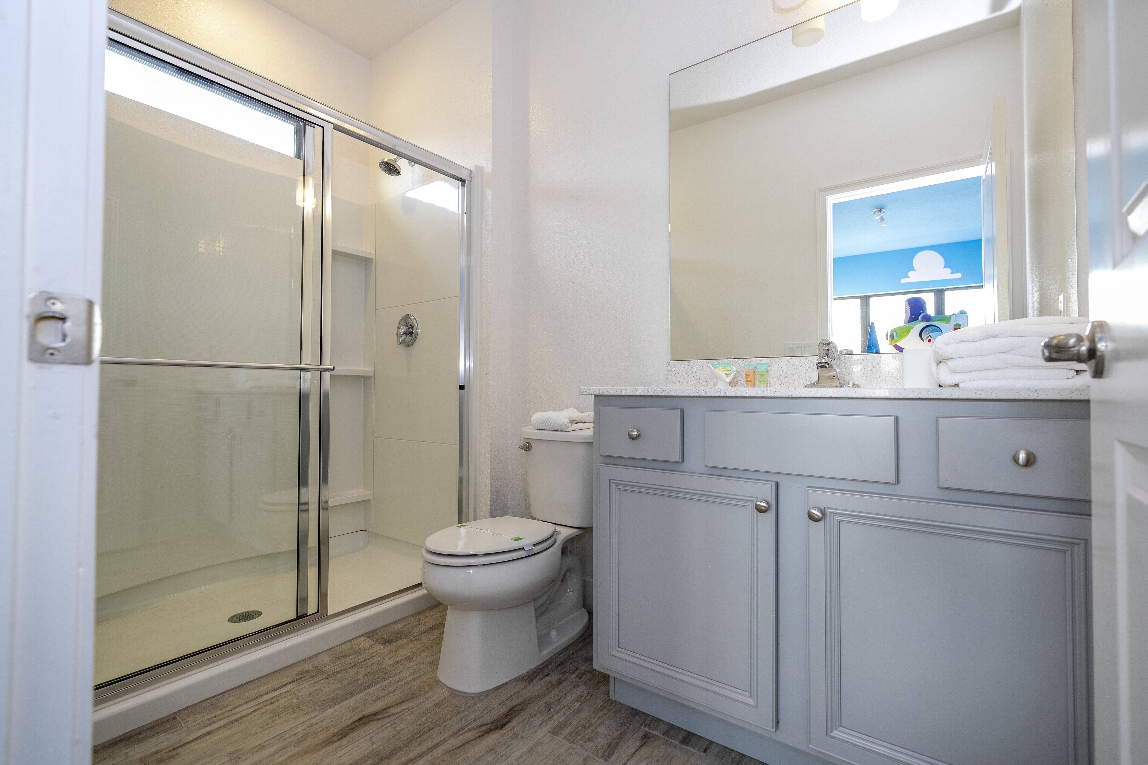 Un baño moderno con ducha envuelta en vidrio, inodoro y tocador con espejo.