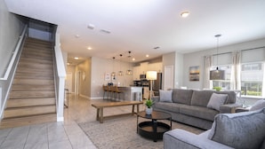 A modern living room with a staircase, a dining area, and a kitchen. - Last Minute Disney Getaway! Private Pool & Themed Bedrooms. Book Now! #127919 (Orlando)