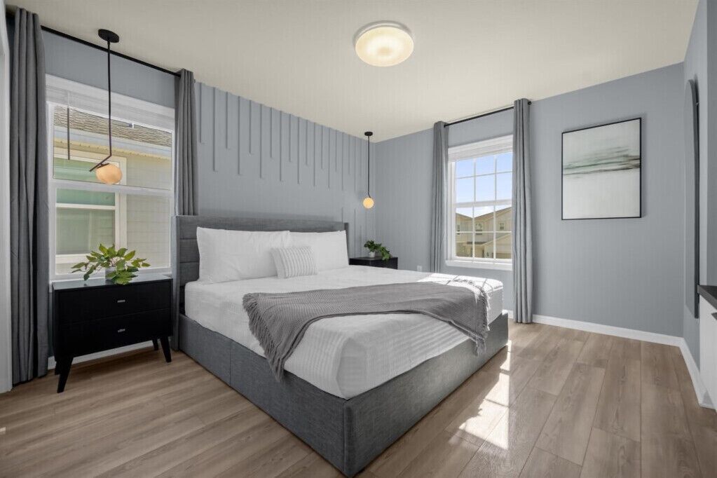 A modern bedroom with a large bed, a bedside table, a nightstand, and a window with curtains.
