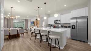 Una cocina moderna con una isla central, electrodomésticos de acero inoxidable e iluminación colgante.