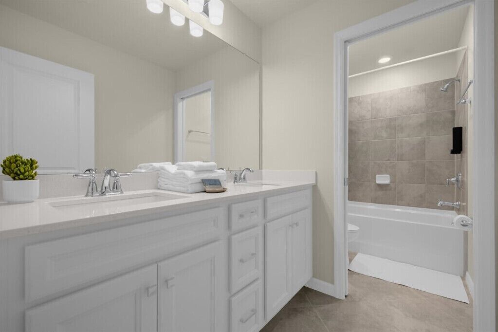 Un baño moderno con un amplio tocador, ducha e inodoro.