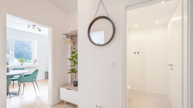Un interior moderno con comedor, espejo y baño.