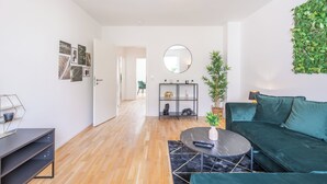 Una sala de estar moderna con un sofá verde, una mesa redonda de centro y una estantería.