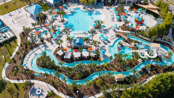 An aerial view of a resort with multiple swimming pools, palm trees, and lounge areas.