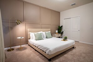 A bedroom with a bed, bedside tables, a floor lamp, and a door.