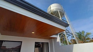 Un bâtiment moderne doté d’un plafond en bois, d’une citerne d’eau et d’une structure métallique.