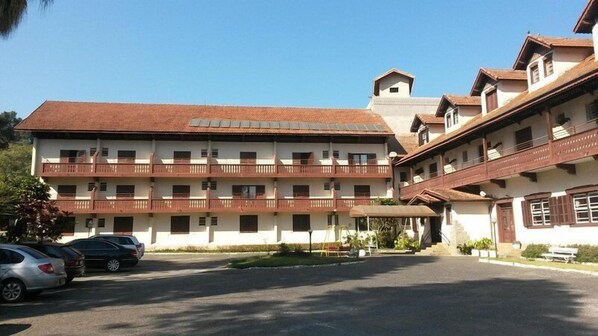 A multi-story hotel with a central courtyard, balconies, and a parking area. - HOTEL FLORESTA (Poços de Caldas)