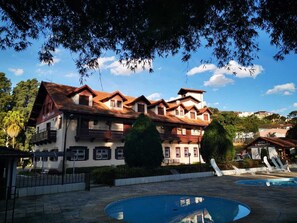 A large building with multiple balconies and a swimming pool area. - HOTEL FLORESTA (Poços de Caldas)