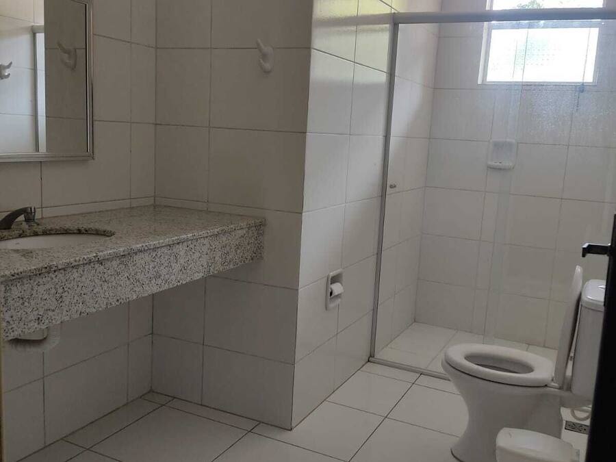 A bathroom with a granite countertop, a toilet, and a shower area.