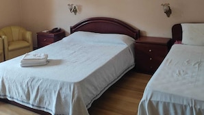 Ein Hotelzimmer mit zwei Betten, einem Deckenventilator, einem Nachttisch mit Lampe und einem Sessel.