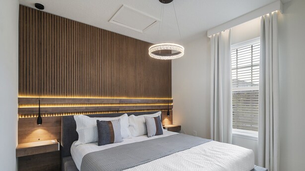 A modern bedroom with a large bed, a wooden slat headboard, a bedside table, and a window with curtains. - Last Minute Disney! Private Pool, Game Room & Themed Bedrooms. Book Now! #120787 (Orlando)