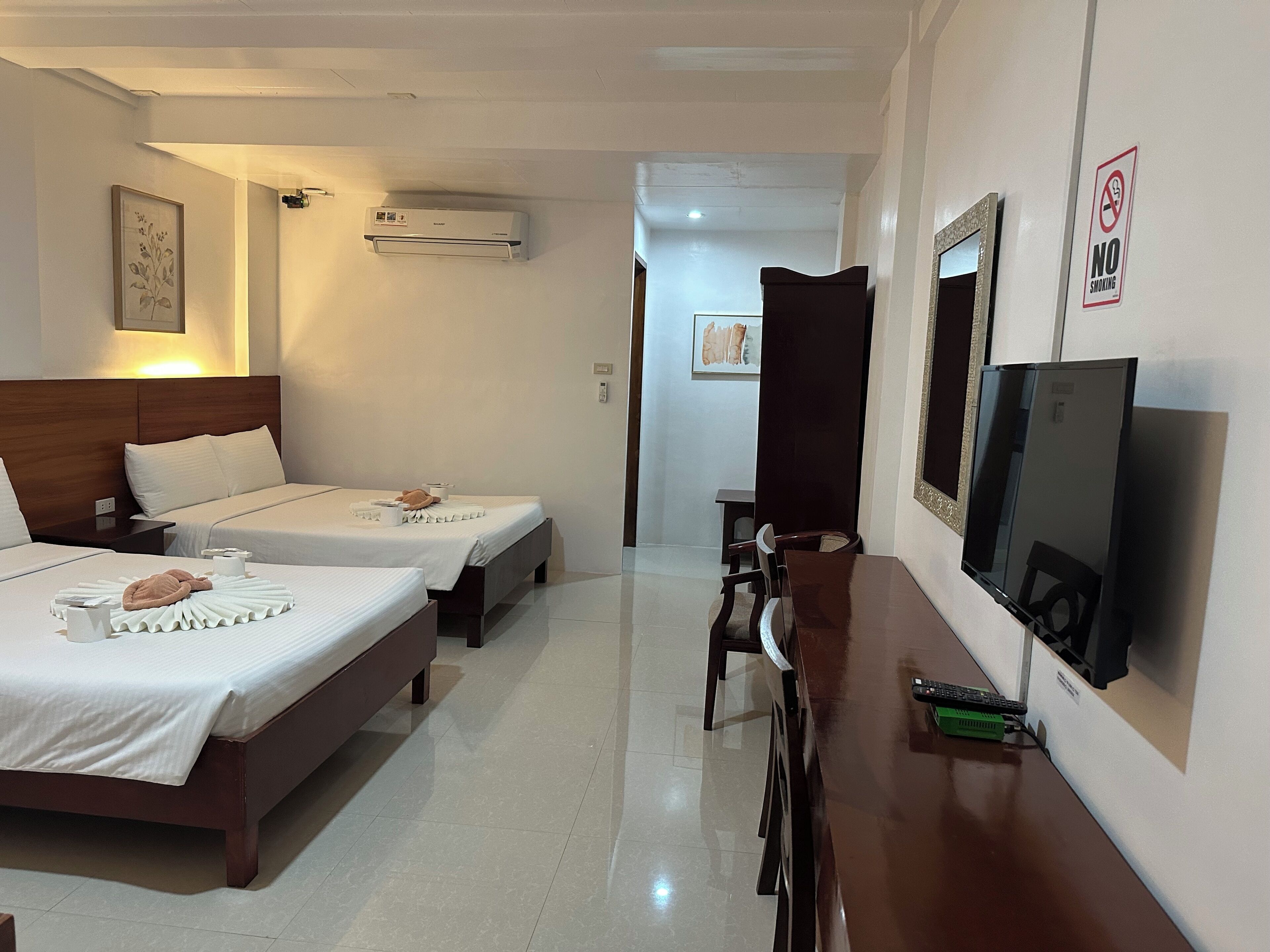 Habitación de hotel con dos camas, televisión y escritorio.