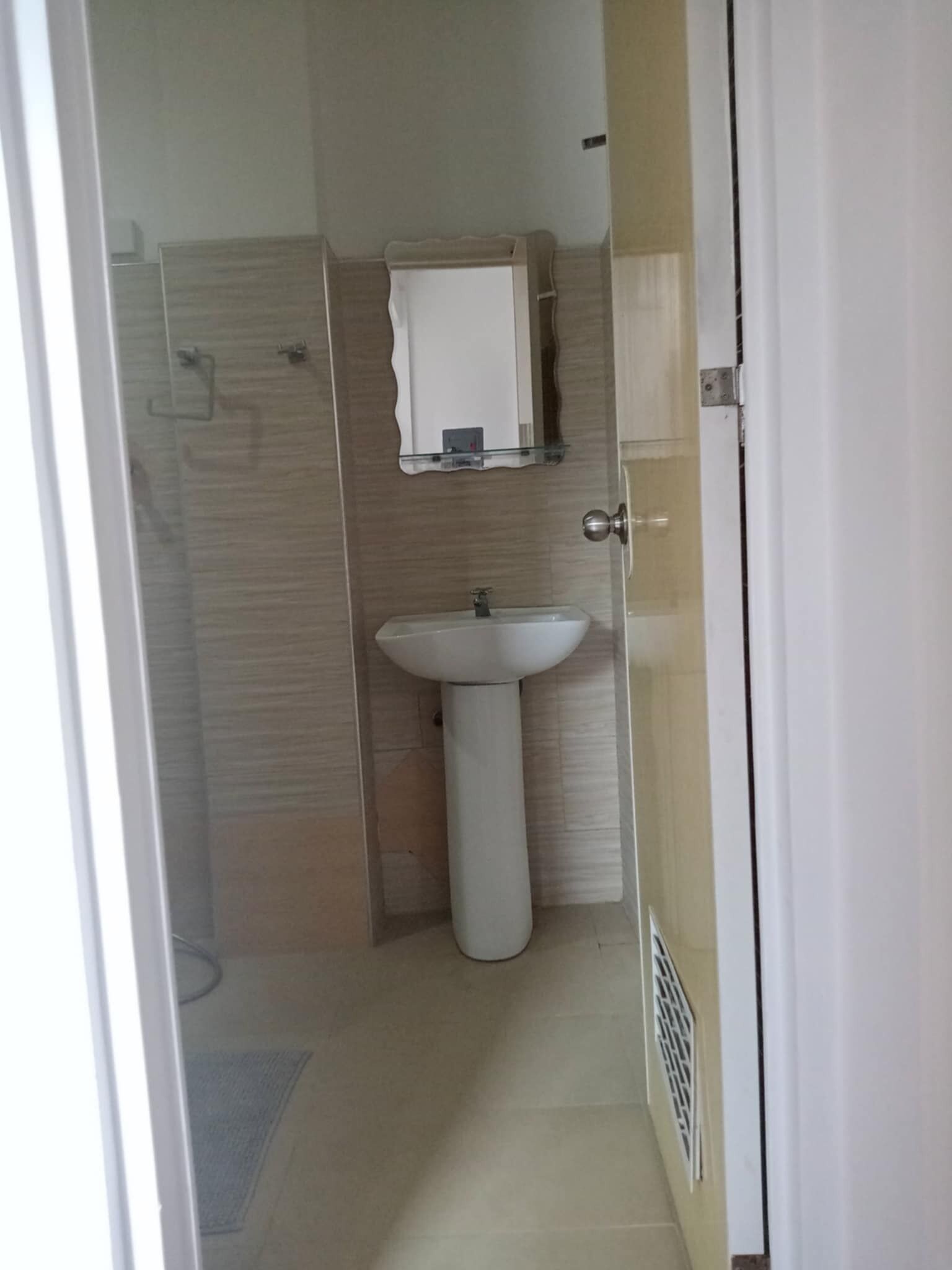 Un baño pequeño con lavamanos pedestal, un espejo y zona de ducha.
