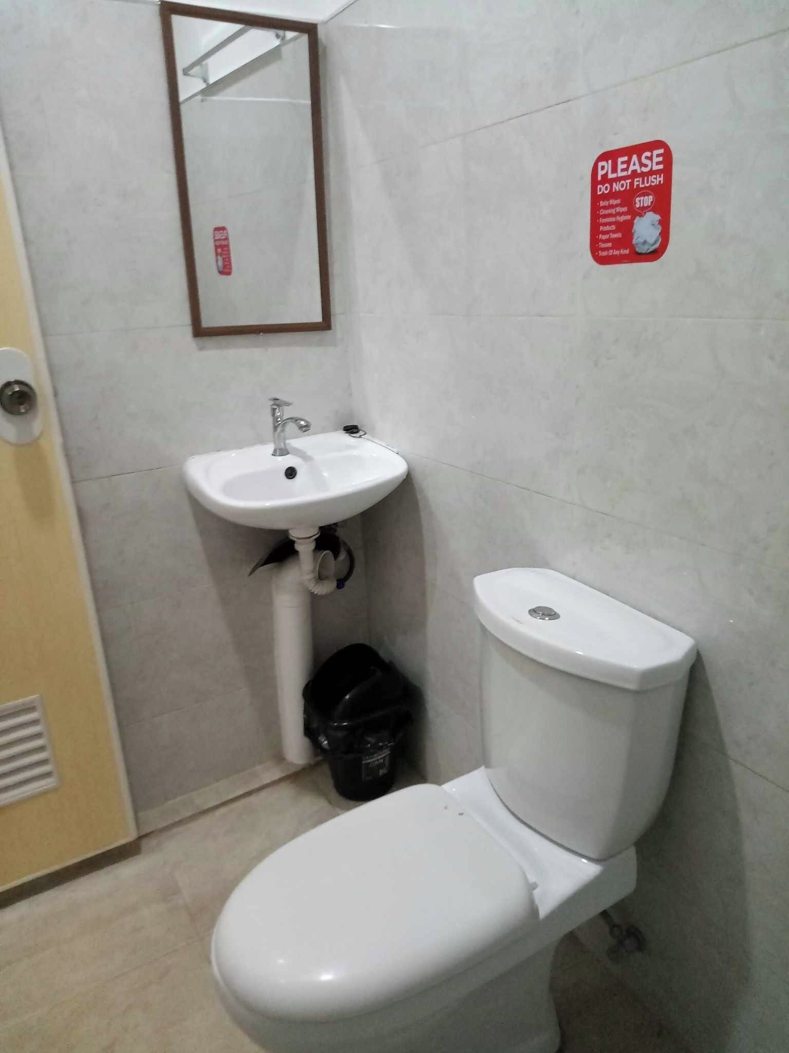 A bathroom with a white sink, toilet, and a mirror on the wall.