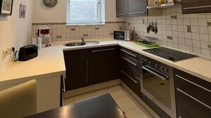 A modern kitchen with a black countertop, stainless steel appliances, and a window above the sink.