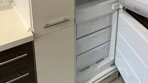 A kitchen with a white cabinet, a white countertop, and a white refrigerator with a freezer compartment.