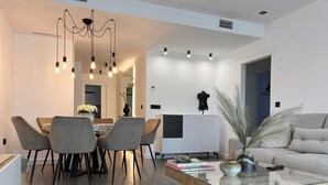 A modern living room with a dining area, featuring a glass coffee table, grey upholstered chairs, and a contemporary chandelier. - Design apartment in Residencial AGUACATE BEACH, golf and beach 5 minutes away.  (AN)