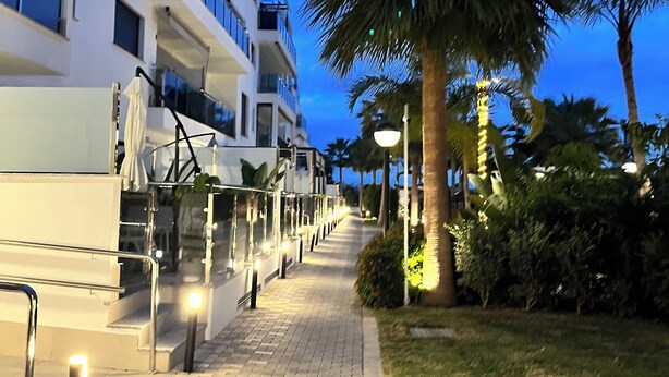 A pathway leading to a modern building with multiple floors, outdoor seating, and palm trees. - Design apartment in Residencial AGUACATE BEACH, golf and beach 5 minutes away.  (AN)