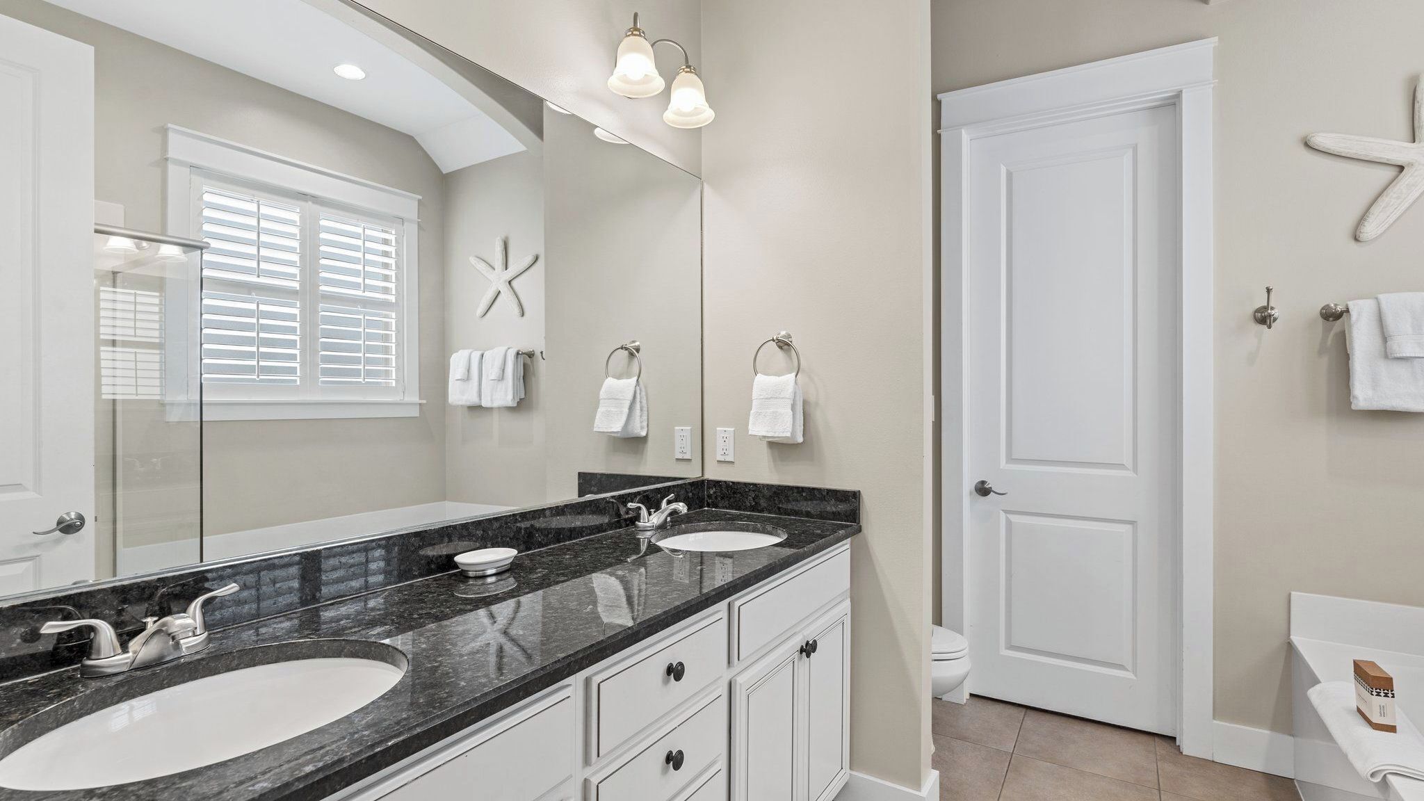 A bathroom with two sinks, a large mirror, and a door.
