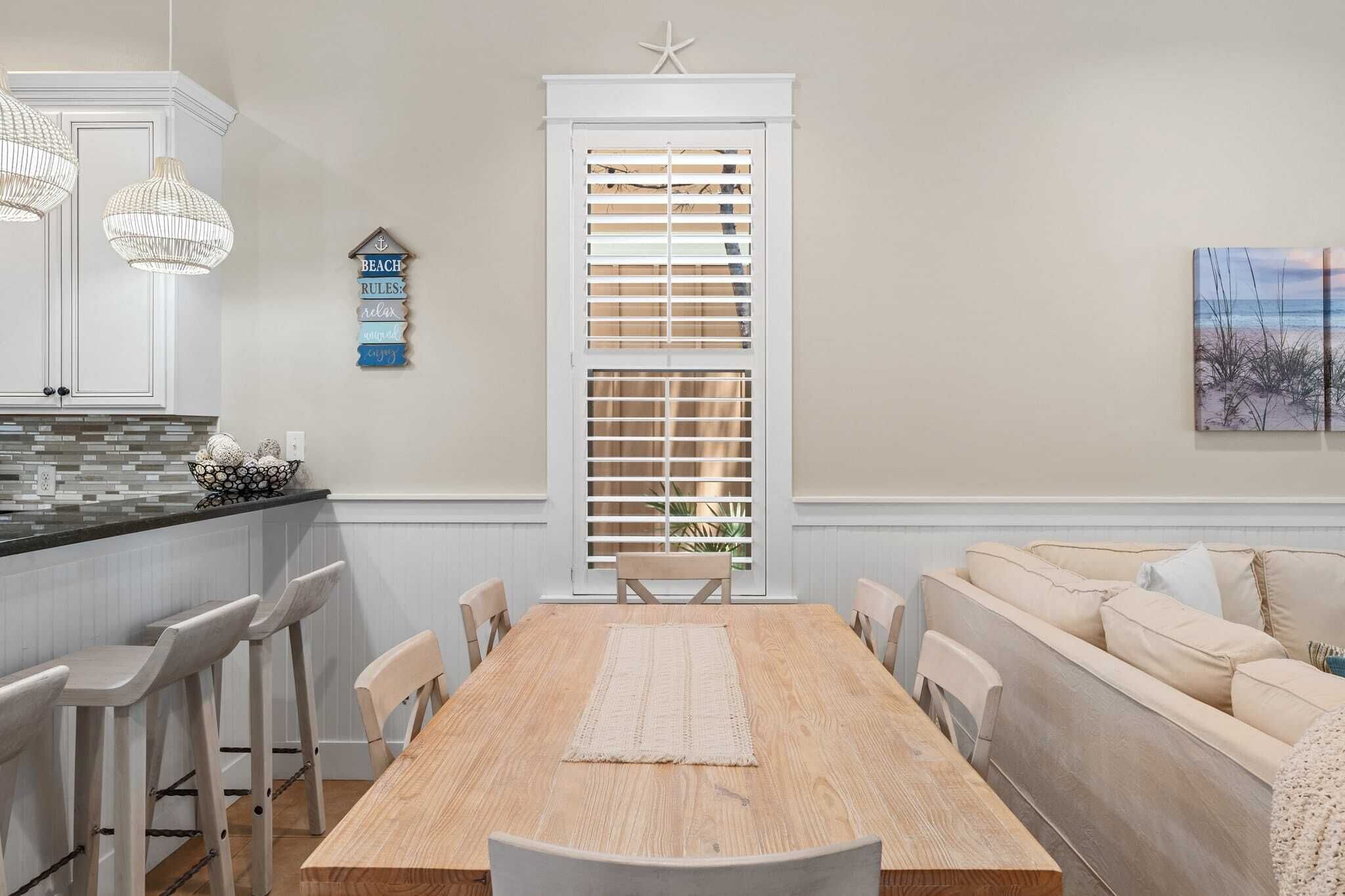 A dining area with a wooden table, white chairs, a beige sofa, and a decorative wall piece.