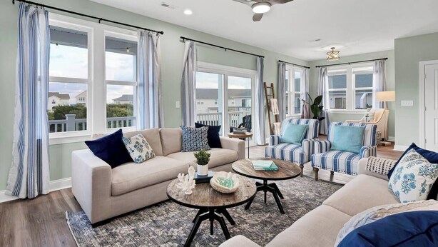 A spacious living room with a beige sofa, striped armchairs, and a round coffee table. - This is How We Roll- Shared Pool! (surf City)