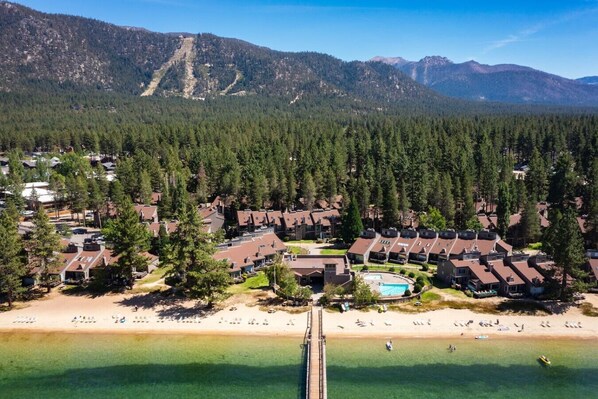 A resort with multiple buildings, a beach, and a mountain backdrop.
