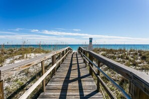 A wooden boardwalk leading to a beach with clear skies.