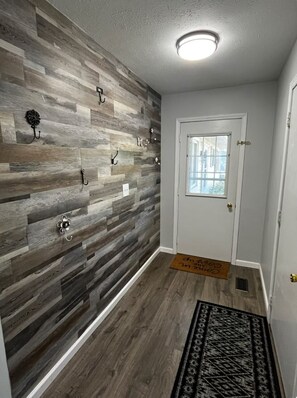 Enter a stylish hallway with a textured wall, patterned rug, and modern door with a glass panel.