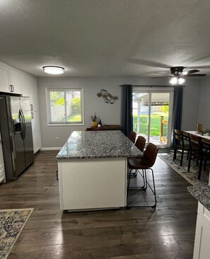 Enjoy meals in the kitchen with a central island, refrigerator, and ample counter space, plus a sliding glass door leading to a patio with outdoor views.