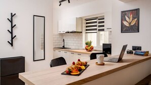 A modern kitchen with white cabinets, a black countertop, and a dining area with a laptop and books.