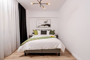 A bedroom with a bed, a bedside table, a lamp, and a wall-mounted artwork.
