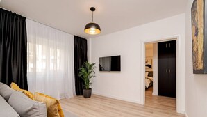 A modern living room with a sofa, a potted plant, and a television.