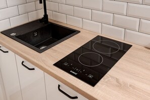 Een keuken met een zwart spoelgedeelte en een zwart inductiekookveld met bedieningspaneel.