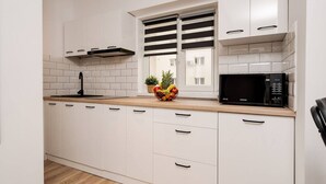 A kitchen with white cabinets, a microwave, and a fruit bowl on the counter.