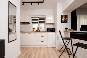 Een moderne keuken met witte kasten, een magnetron en een fruitschaal op het aanrecht.