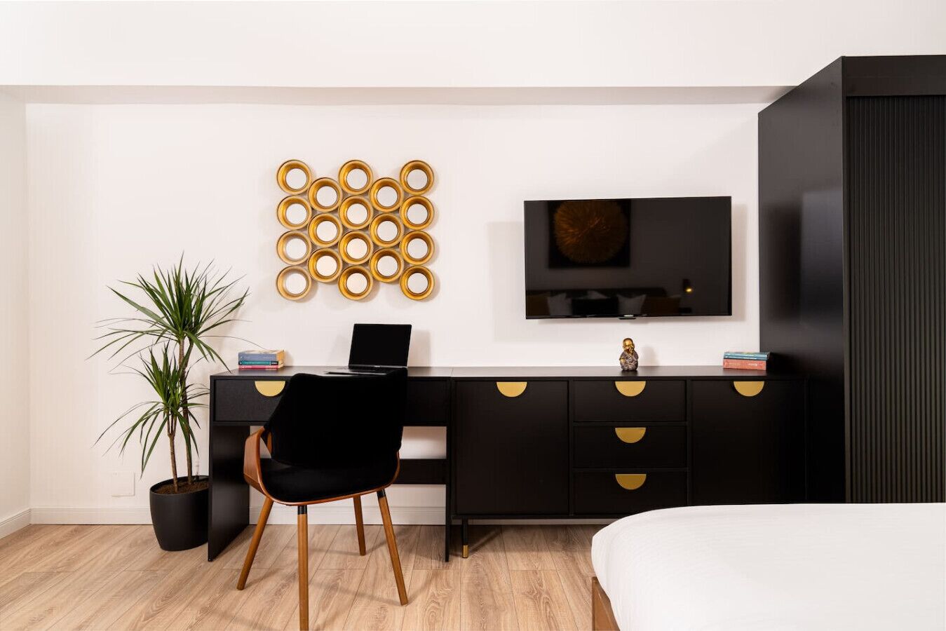 Un dormitorio moderno con un escritorio negro, un televisor y una cama.