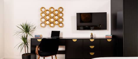 A modern bedroom with a black desk, a TV, and a bed.