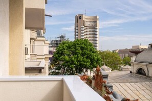 A hotel with a rooftop terrace featuring a large tree and classical architectural elements. - Tyst by MRG Apartments | City Centre Spacious Cozy Apartment with Balcony (București)