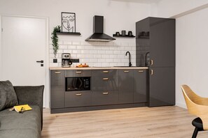 Modern kitchen with oven, microwave, and stainless steel sink, complemented by a grey cabinet and black refrigerator.