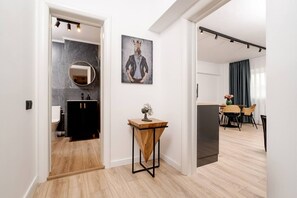 A modern interior with a dining area, a kitchen, and a bathroom. - Tyst by MRG Apartments | City Centre Spacious Cozy Apartment with Balcony (București)