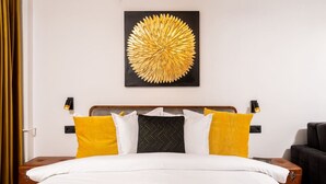 A hotel room with a bed, a headboard, two bedside tables, and a wall-mounted artwork. - Tyst by MRG Apartments | City Centre Spacious Cozy Apartment with Balcony (București)