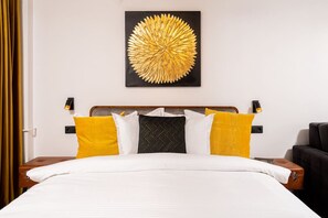 A hotel room with a bed, a headboard, two bedside tables, and a wall-mounted artwork. - Tyst by MRG Apartments | City Centre Spacious Cozy Apartment with Balcony (București)