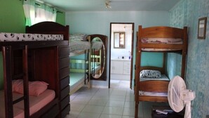 A room with bunk beds, a fan, and a view of a bathroom. - Bed and breakfast in a single suite  (Alto Paraíso de Goiás)