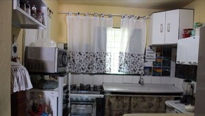 A compact kitchen with a refrigerator, microwave, stove, and sink. - Bed and breakfast in a single suite  (Alto Paraíso de Goiás)