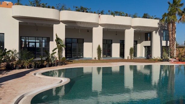 A modern building with a swimming pool, large windows, and palm trees. - Yin Hotel (Marrakech)