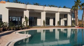 A modern building with a swimming pool, large windows, and palm trees. - Yin Hotel (Marrakech)