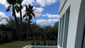 A rectangular swimming pool with clear blue water, surrounded by a white pool deck and a modern building with large windows. - Yin Hotel (Marrakech)