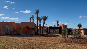 A modern building with a flat roof, large windows, and a paved area with palm trees. - Yin Hotel (Marrakech)