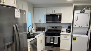A modern kitchen with white cabinetry, stainless steel appliances, and a wooden floor. - Cozy and relaxing apartment with Free WiFi located in vibrant Atlanta. (Atlanta)