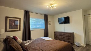 A bedroom with a large bed, a dresser, a television on the wall, and a window with blinds. - Cozy and relaxing apartment with Free WiFi located in vibrant Atlanta. (Atlanta)